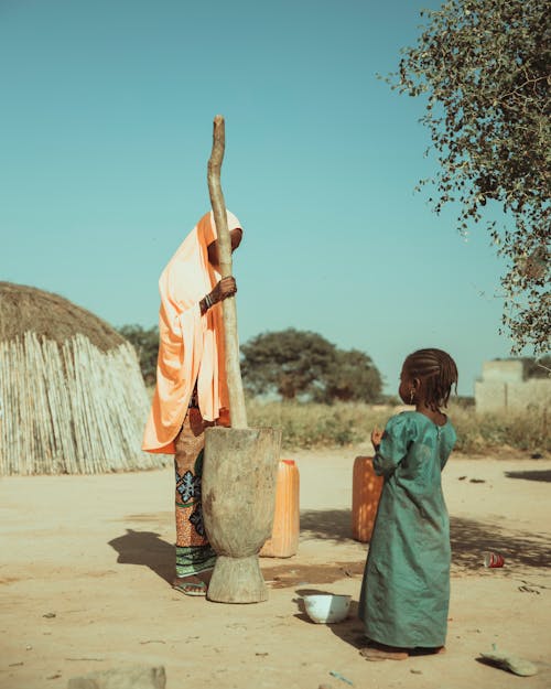 Free A woman and child are standing in front of a hut Stock Photo