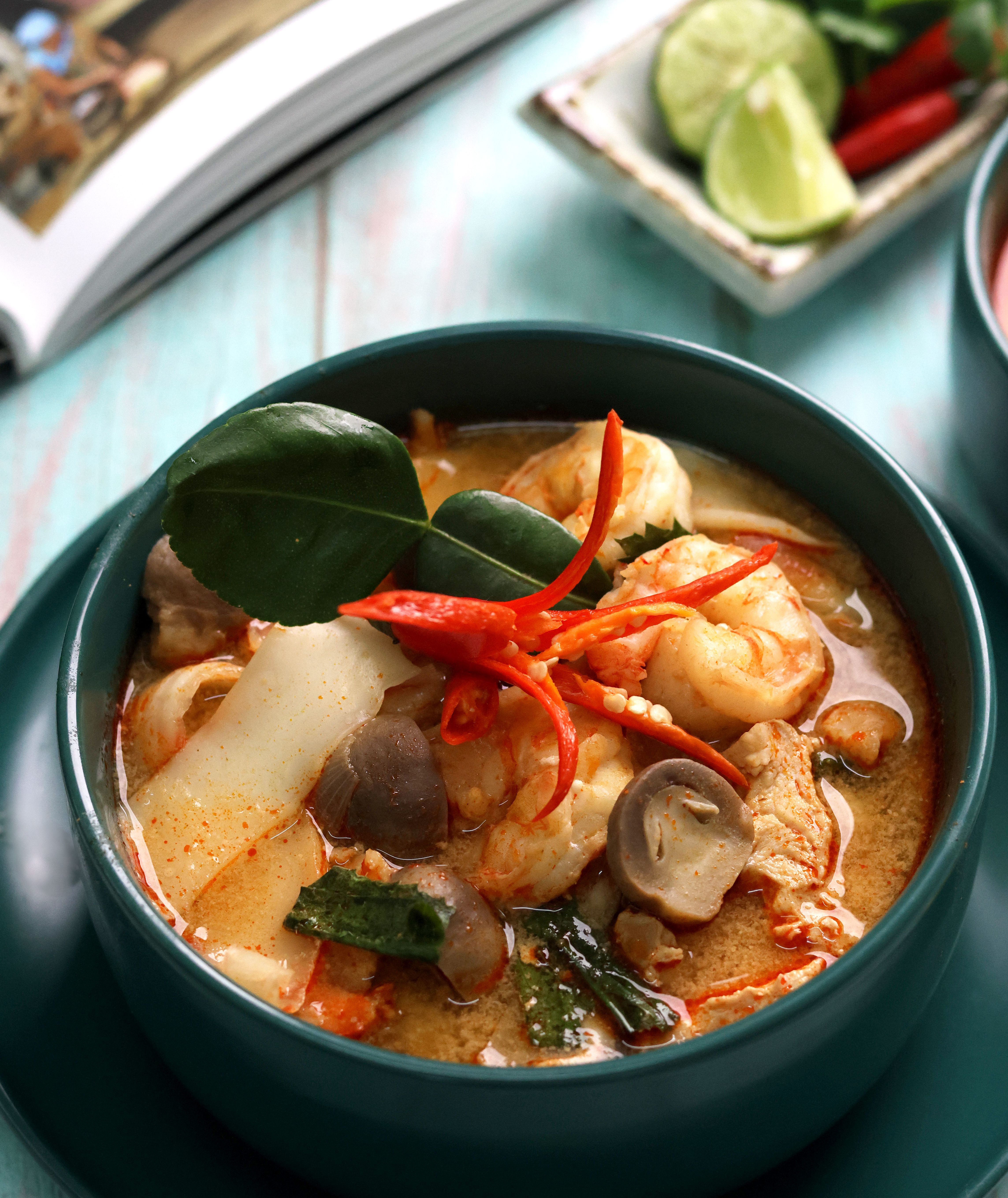 Bol de soupe épicée aux crevettes, champignons, piments rouges et feuilles parfumées