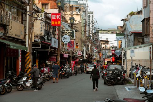 Free A lively urban street scene in Asia featuring motor scooters and pedestrians, with vibrant signs and shops. Stock Photo