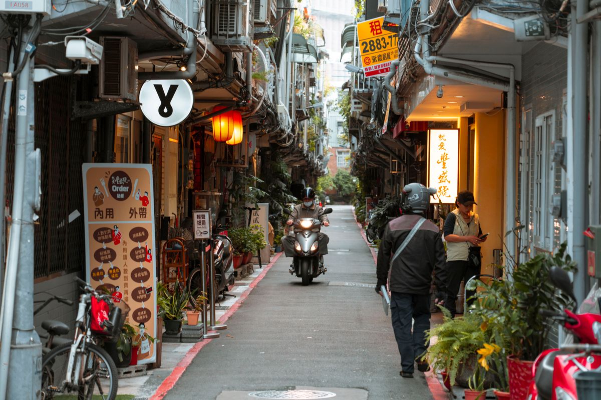 Bustling Taipei alley lined with scooters and small eateries near Shilin Night Market