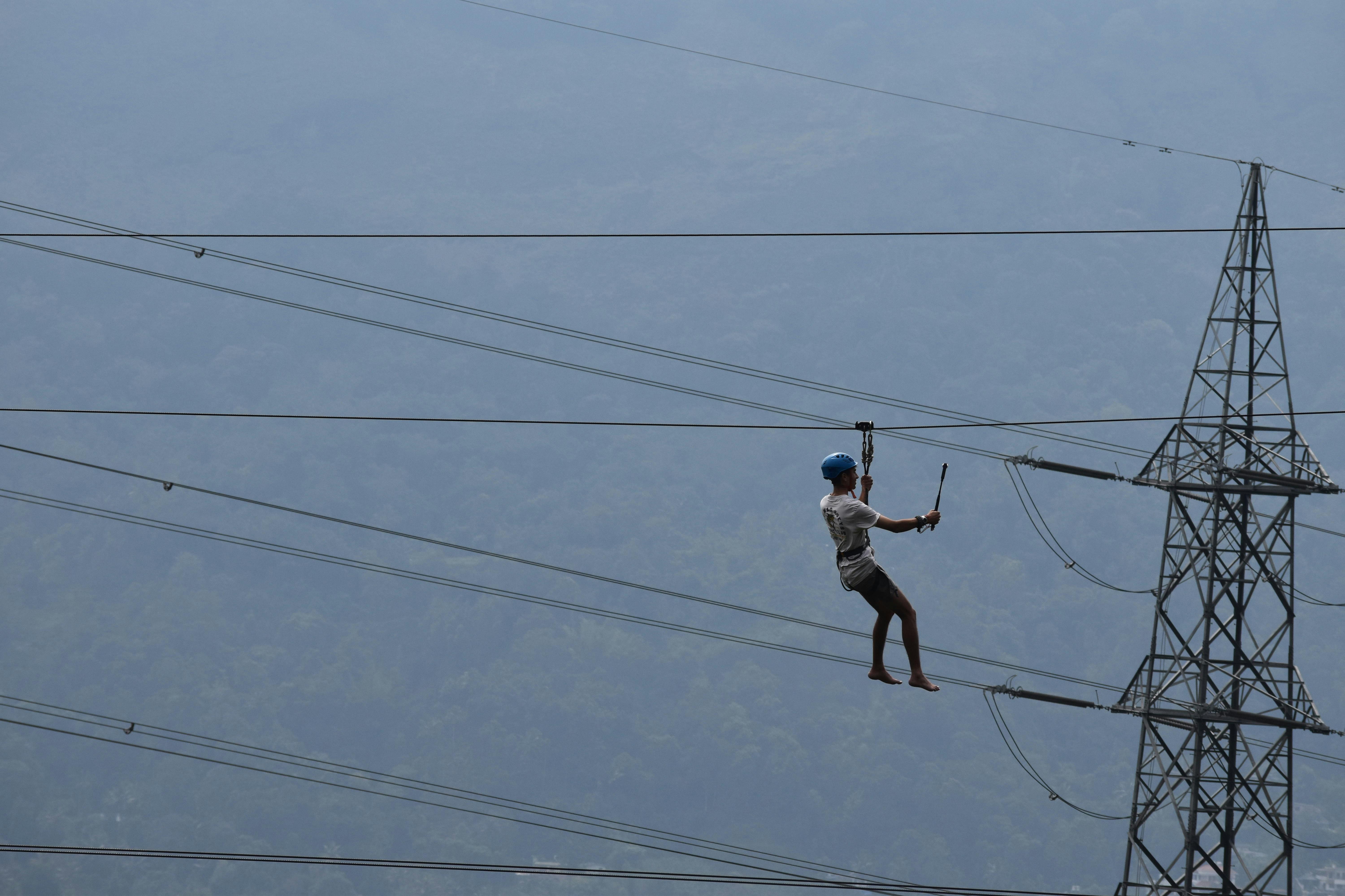 High-altitude worker inspects power lines, emphasizing safety and risk in industrial work.