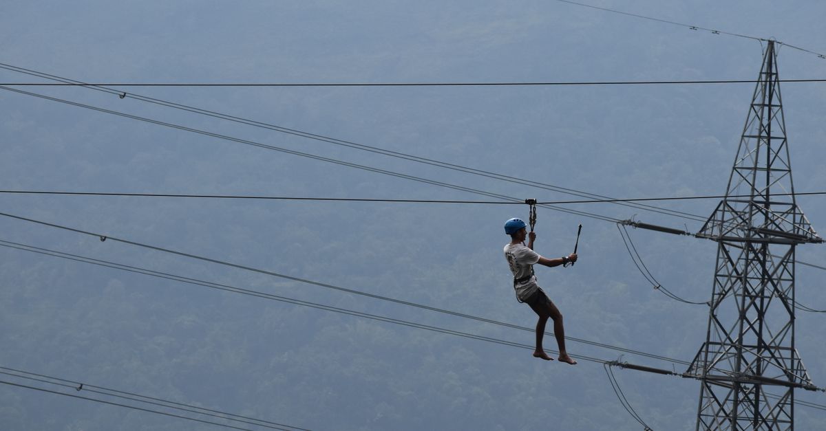 High-altitude worker inspects power lines, emphasizing safety and risk in industrial work.