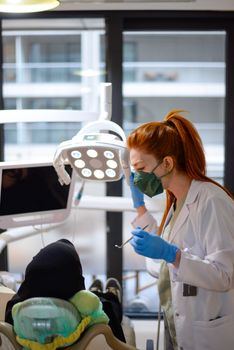 A female dentist conducts a dental checkup in a modern clinic, wearing surgical gloves and a mask.