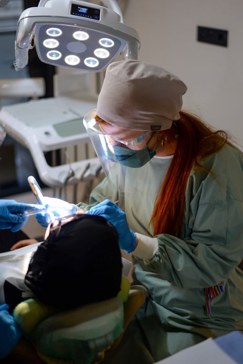 Free A female dentist in protective gear performs a procedure on a patient in a dental clinic. Stock Photo