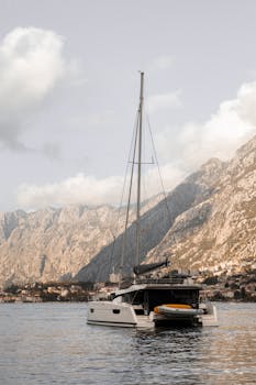Serene sailboat floating on Kotor Bay with stunning mountain backdrop in Montenegro.