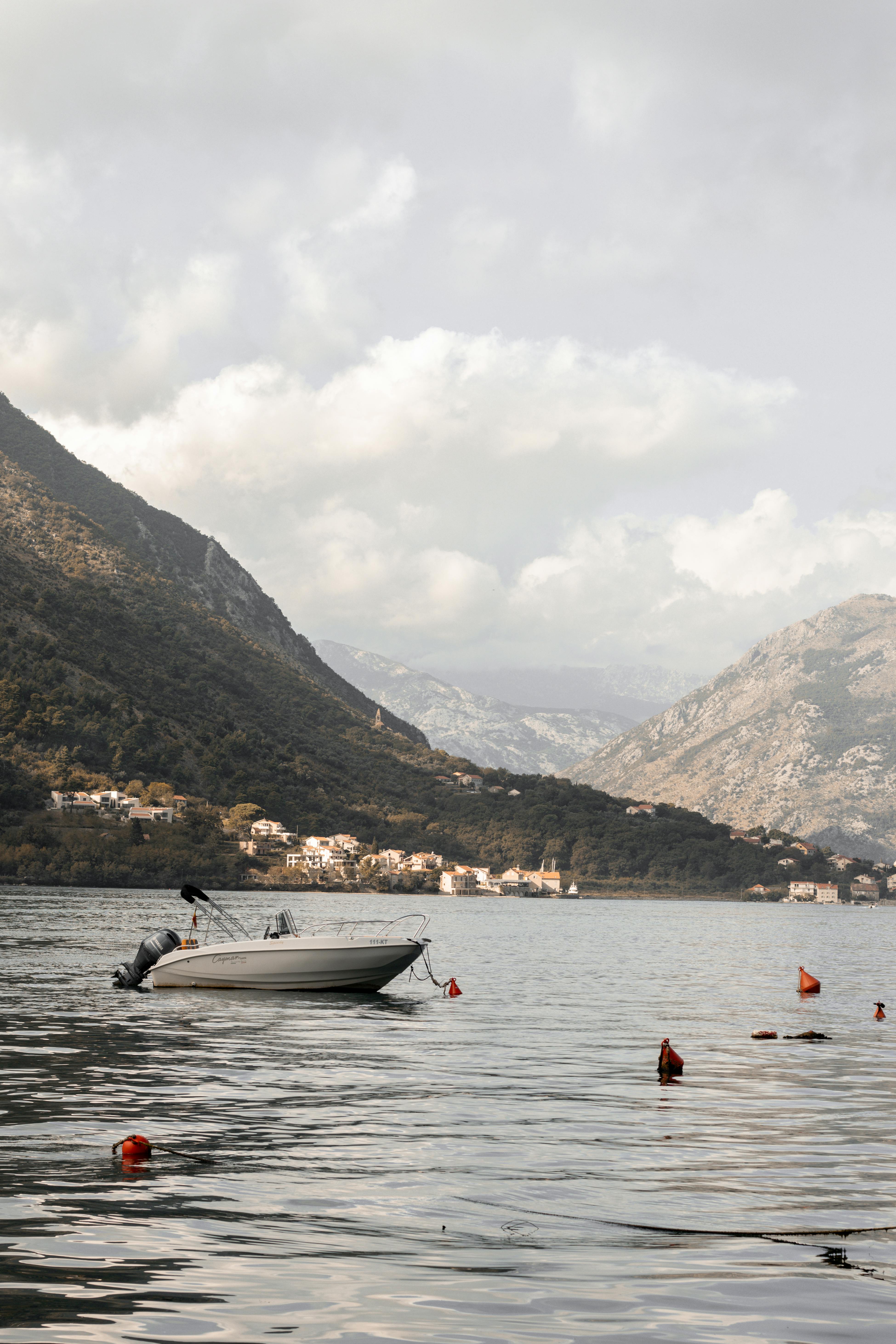 Serene scene of a boat on Kotor Bay with picturesque mountain views in Montenegro.