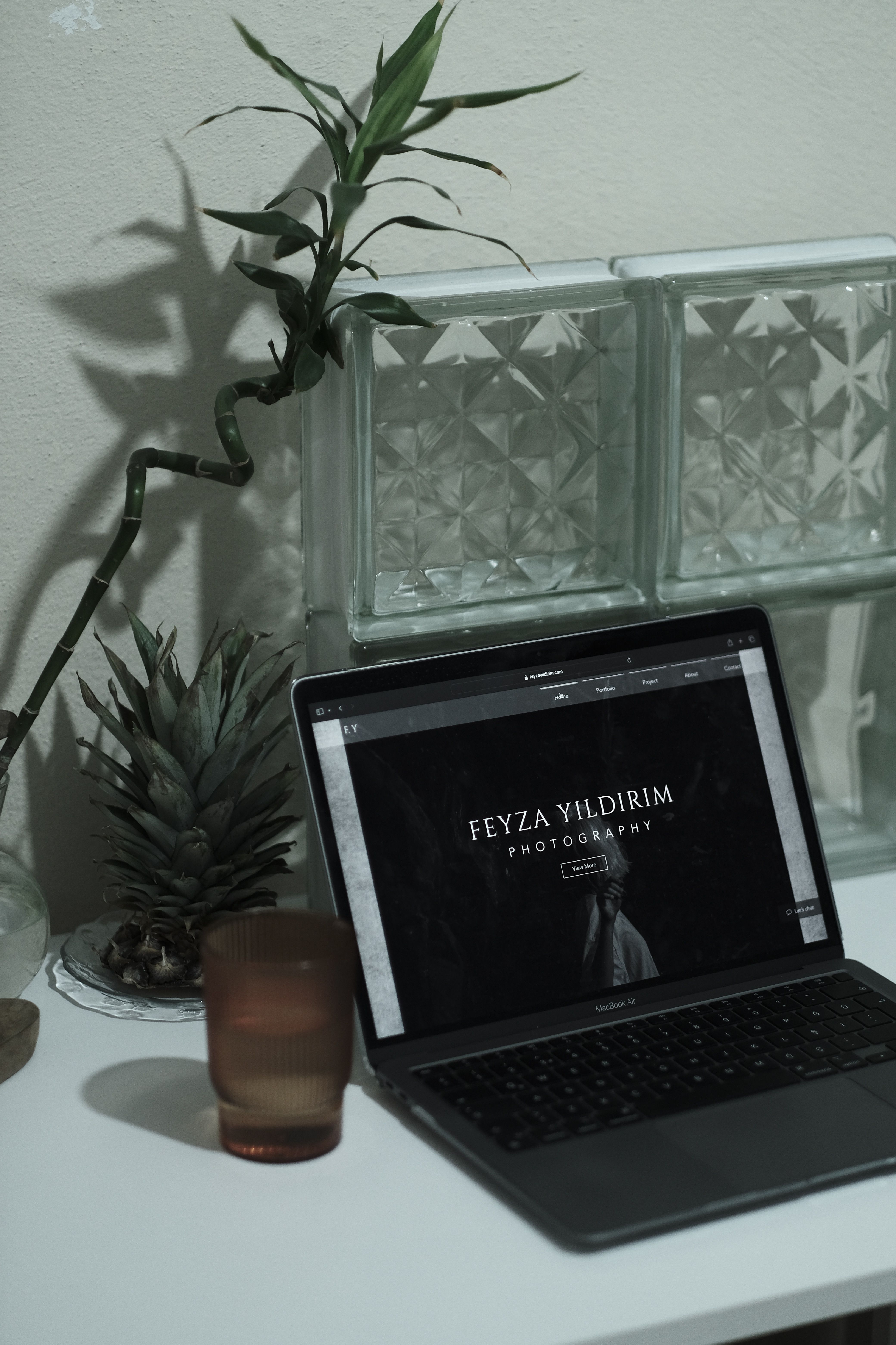 Modern workspace featuring a laptop, glass decor, and bamboo plant for a serene work environment.