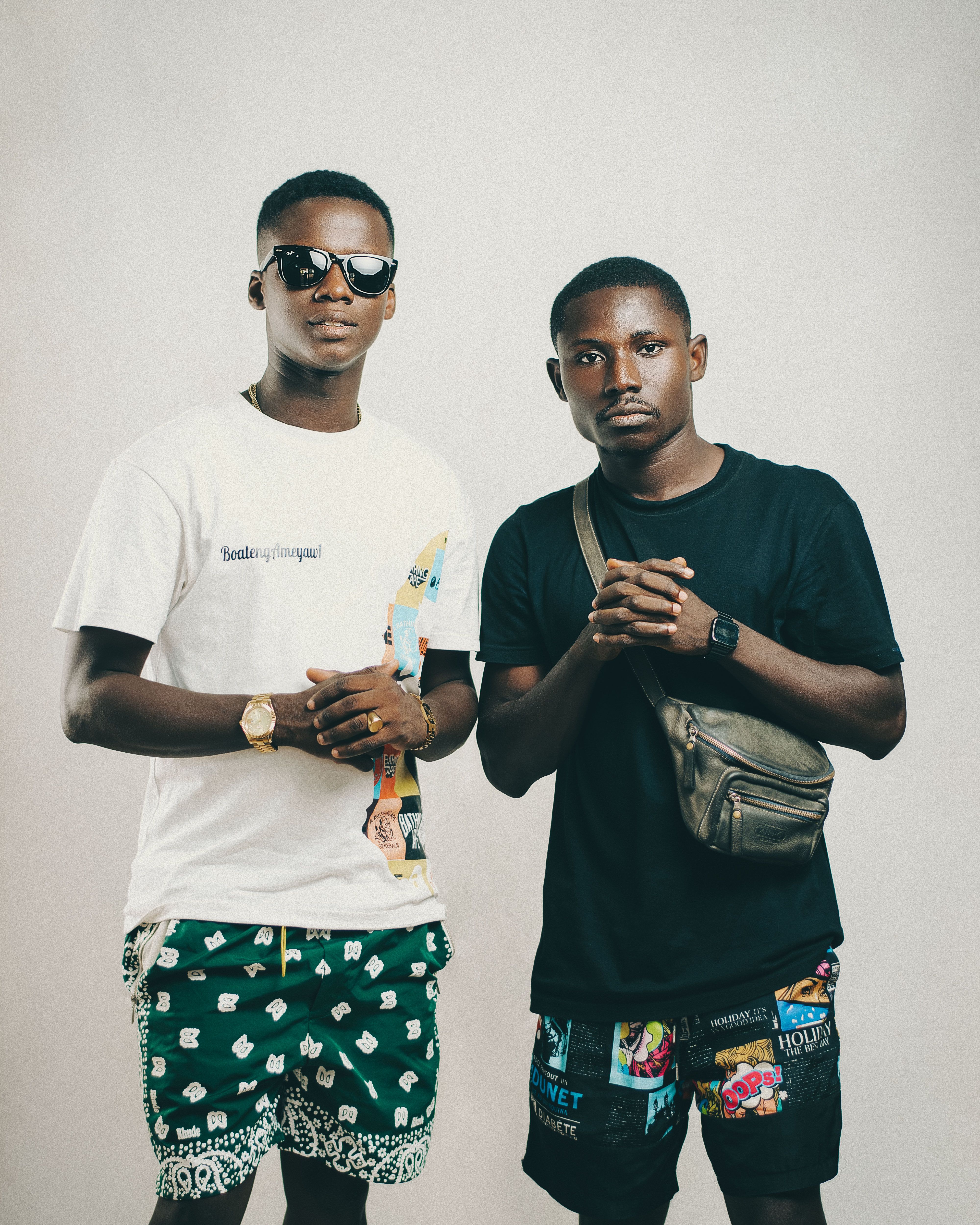 Two stylish African men in colorful shorts posing in a studio setting.