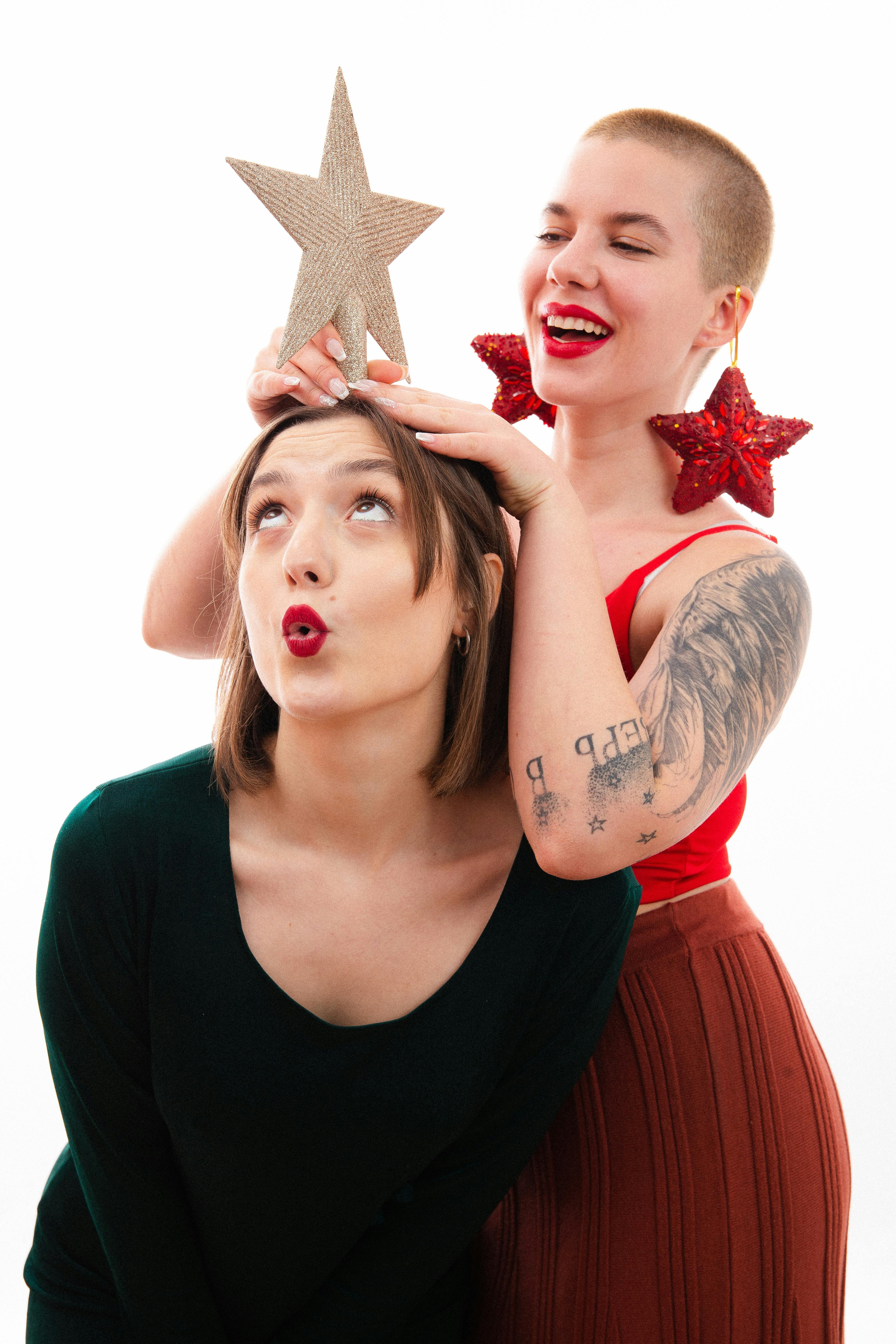Two women enjoying holiday fun with Christmas decorations and joyful expressions.