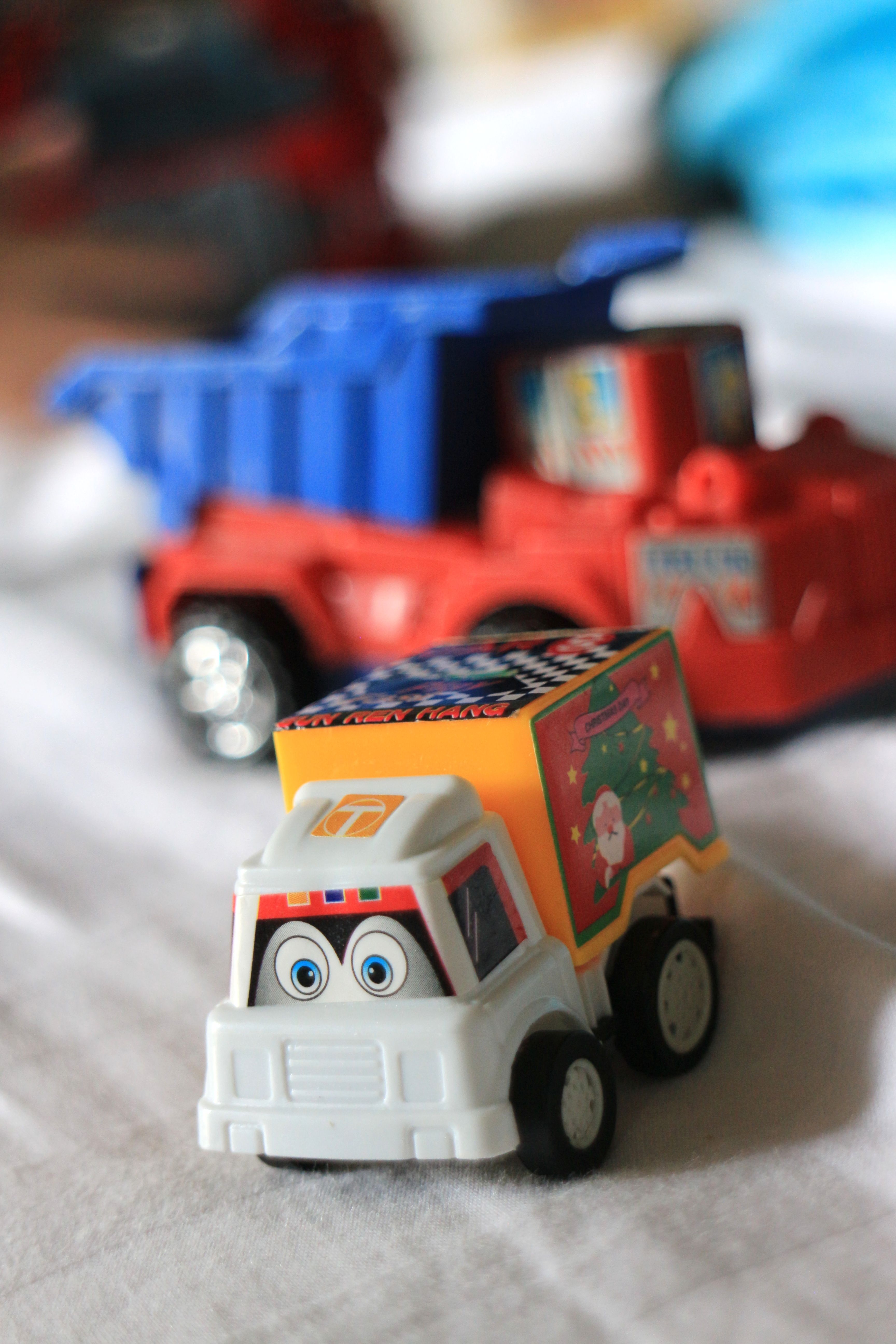 Close-up of small colorful toy trucks on a white background with selective focus.