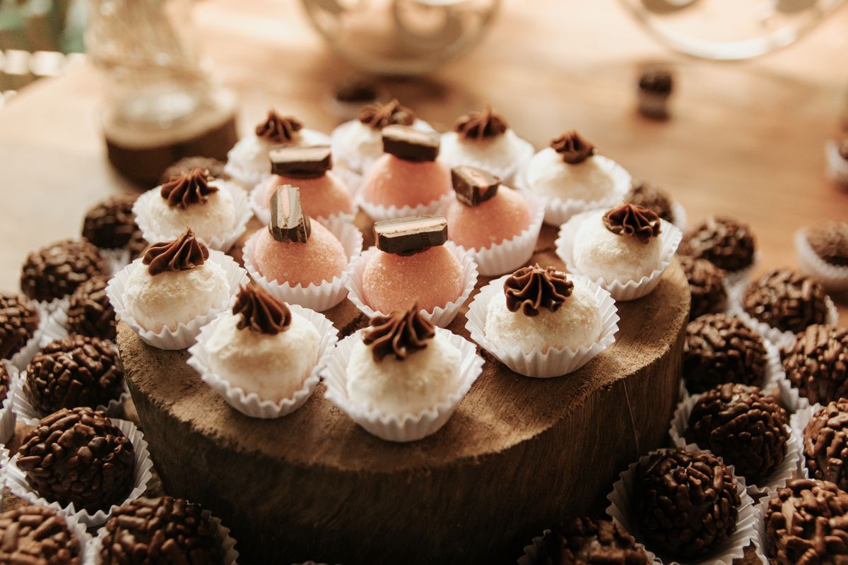 Close-up of assorted handmade Brazilian sweets including brigadeiros and beijinhos on a wooden platter.