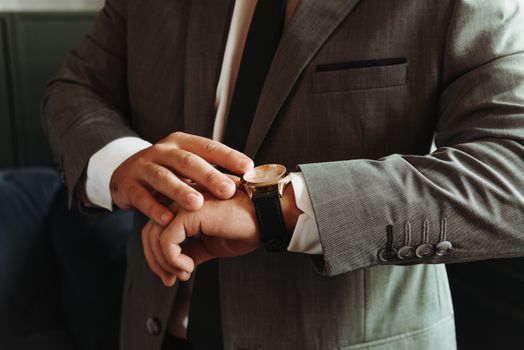 Close-up of a businessman adjusting his wristwatch, showcasing elegance and punctuality.