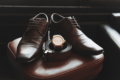 Elegant Brown Shoes, Leather Belt, and Wristwatch Lying on a Chair