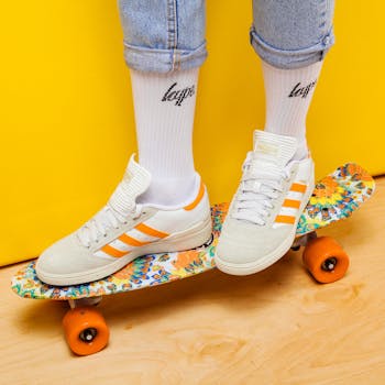 Youthful white and orange sneakers on a colorful skateboard, showcasing fun fashion.
