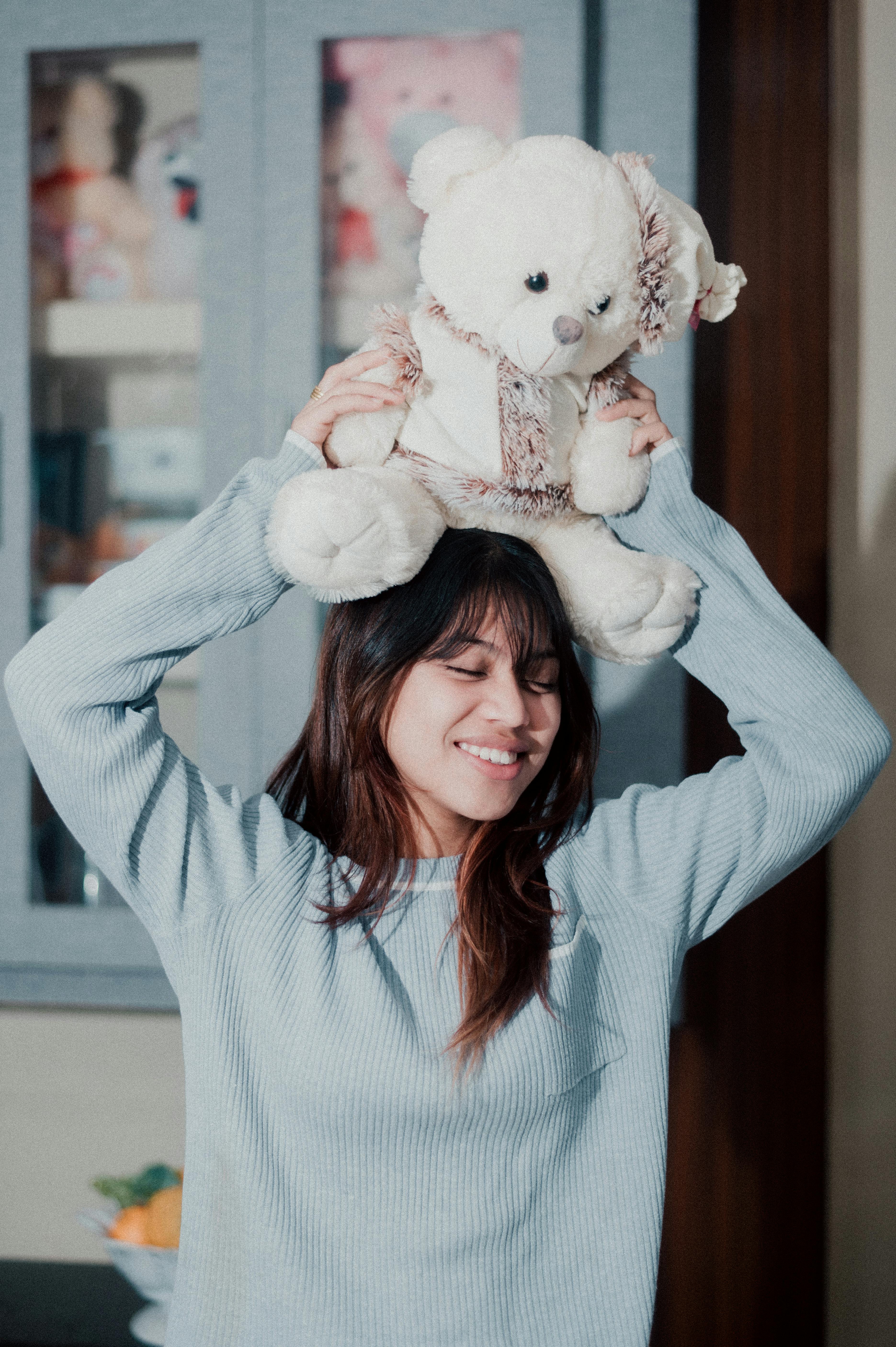 woman holding teddy bear on head