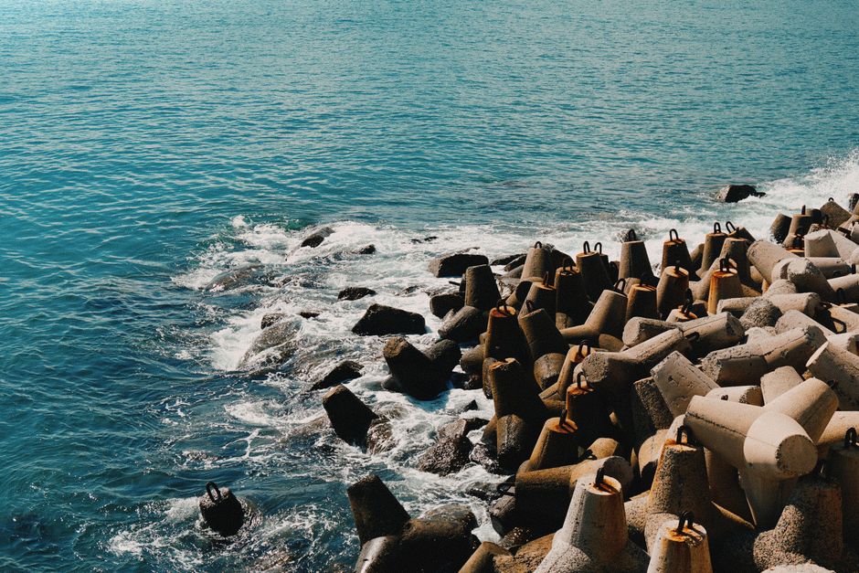 Concrete breakers form a rugged coastline as waves crash against them. Scenic ocean view.
