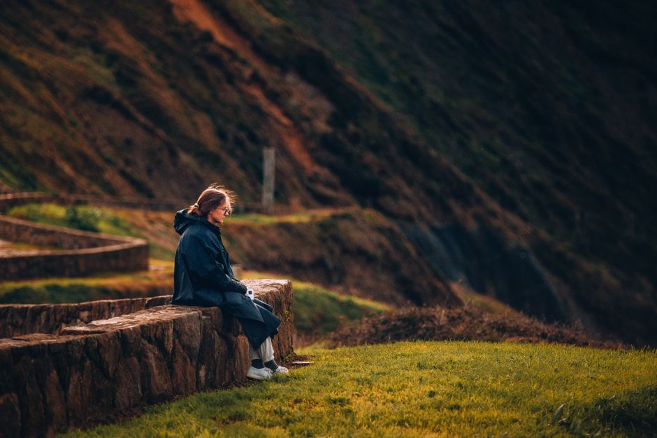 Woman sitting on stone wall in Bilbao enjoying the scenic hillside view.
