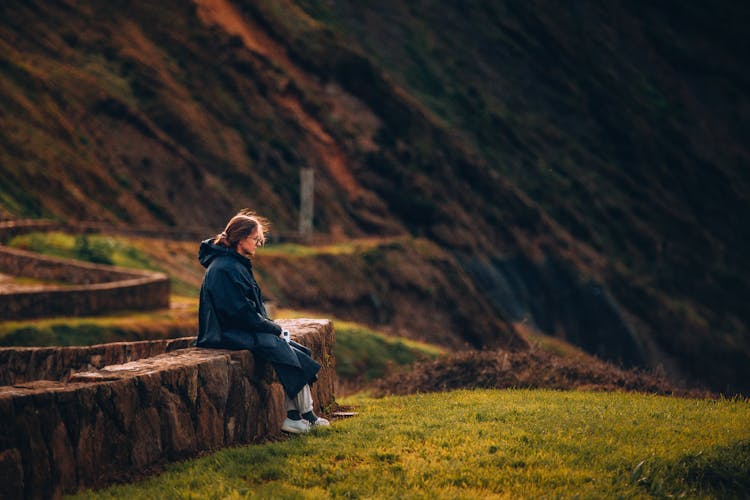 Woman Sitting On The Wall In The Mountains 