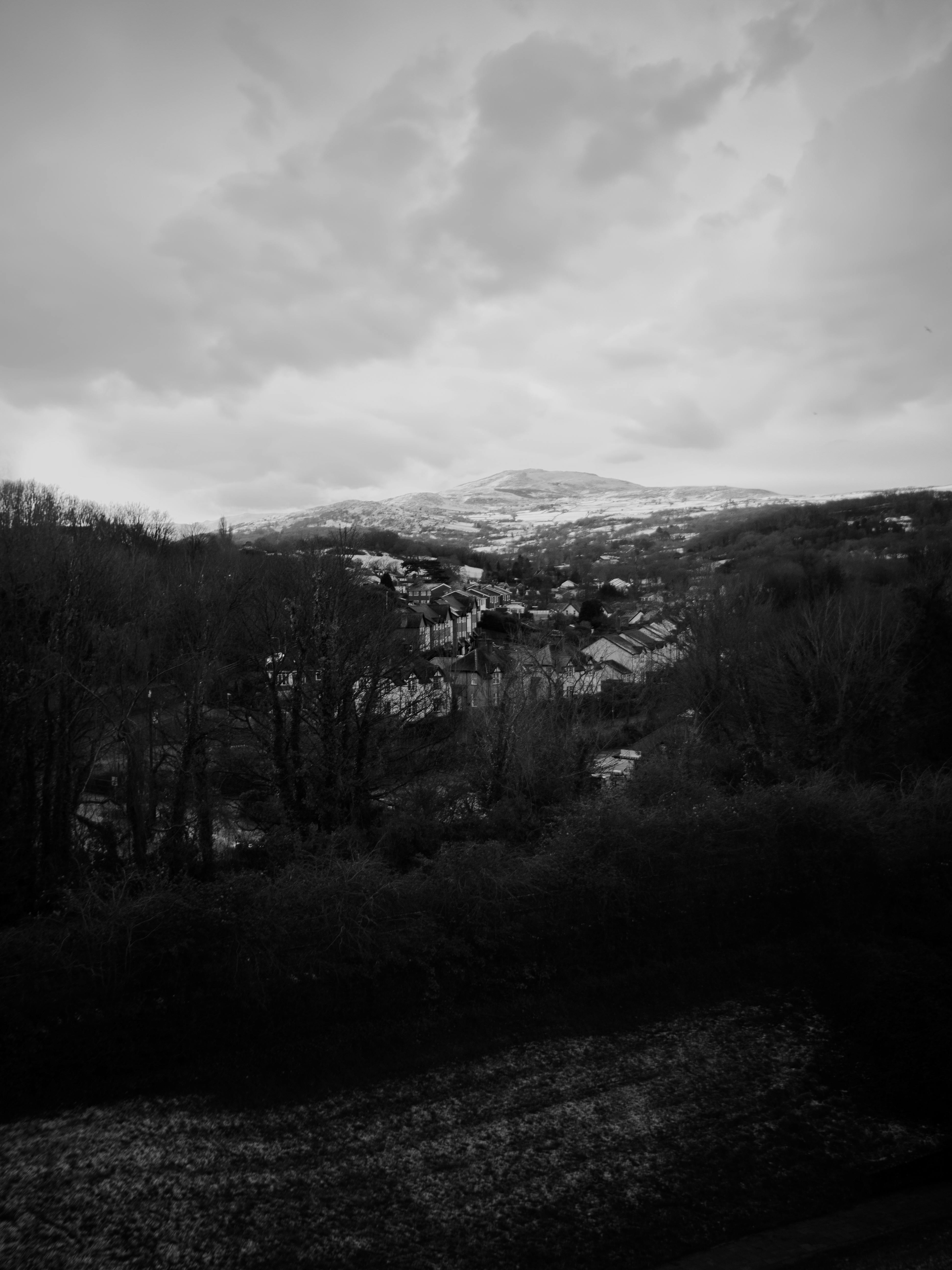 Black and white aerial view of Conwy, Wales with mountains and trees.