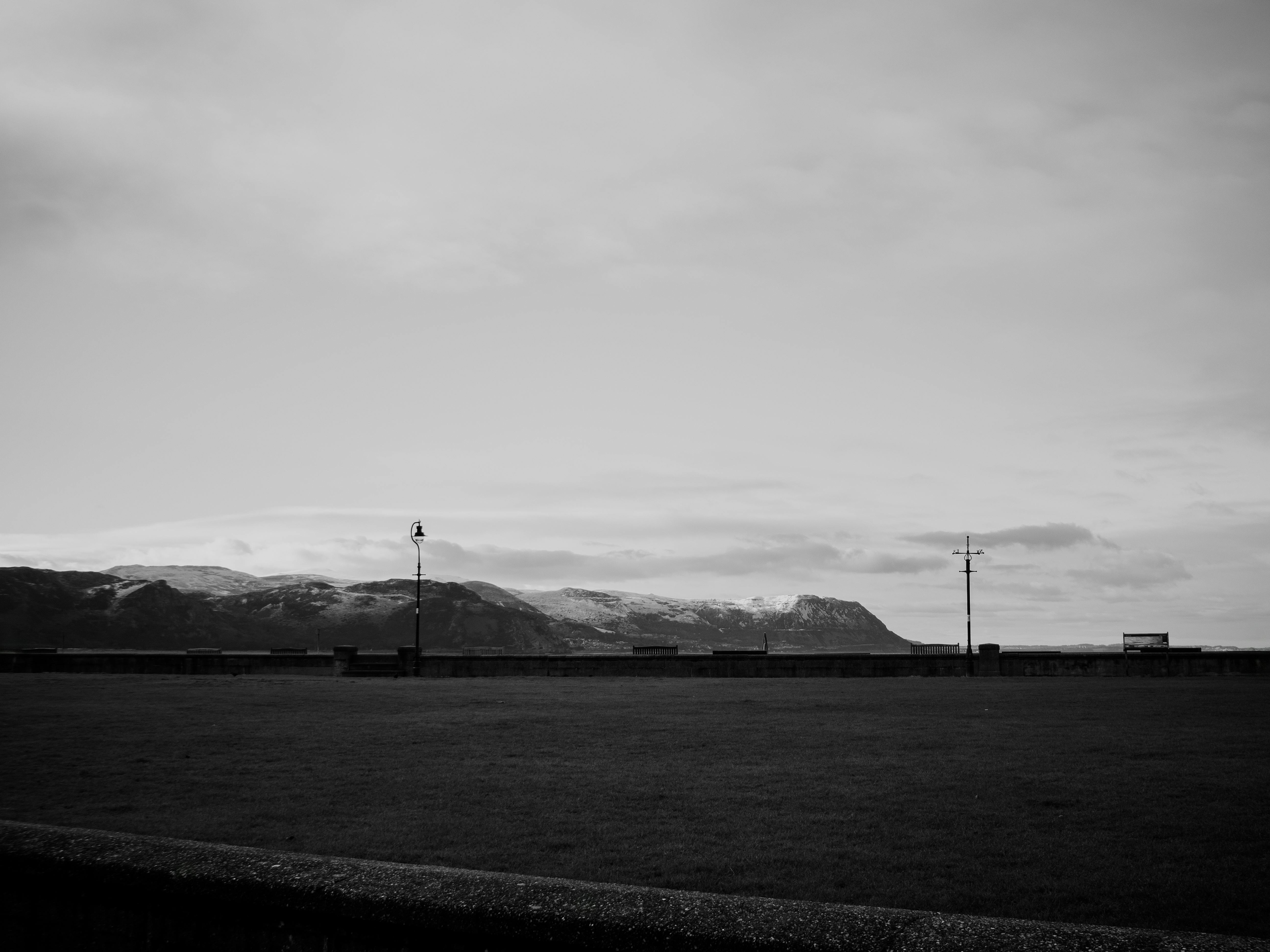 A tranquil black and white countryside view of Llandudno, Wales, featuring hills and distant street lamps.