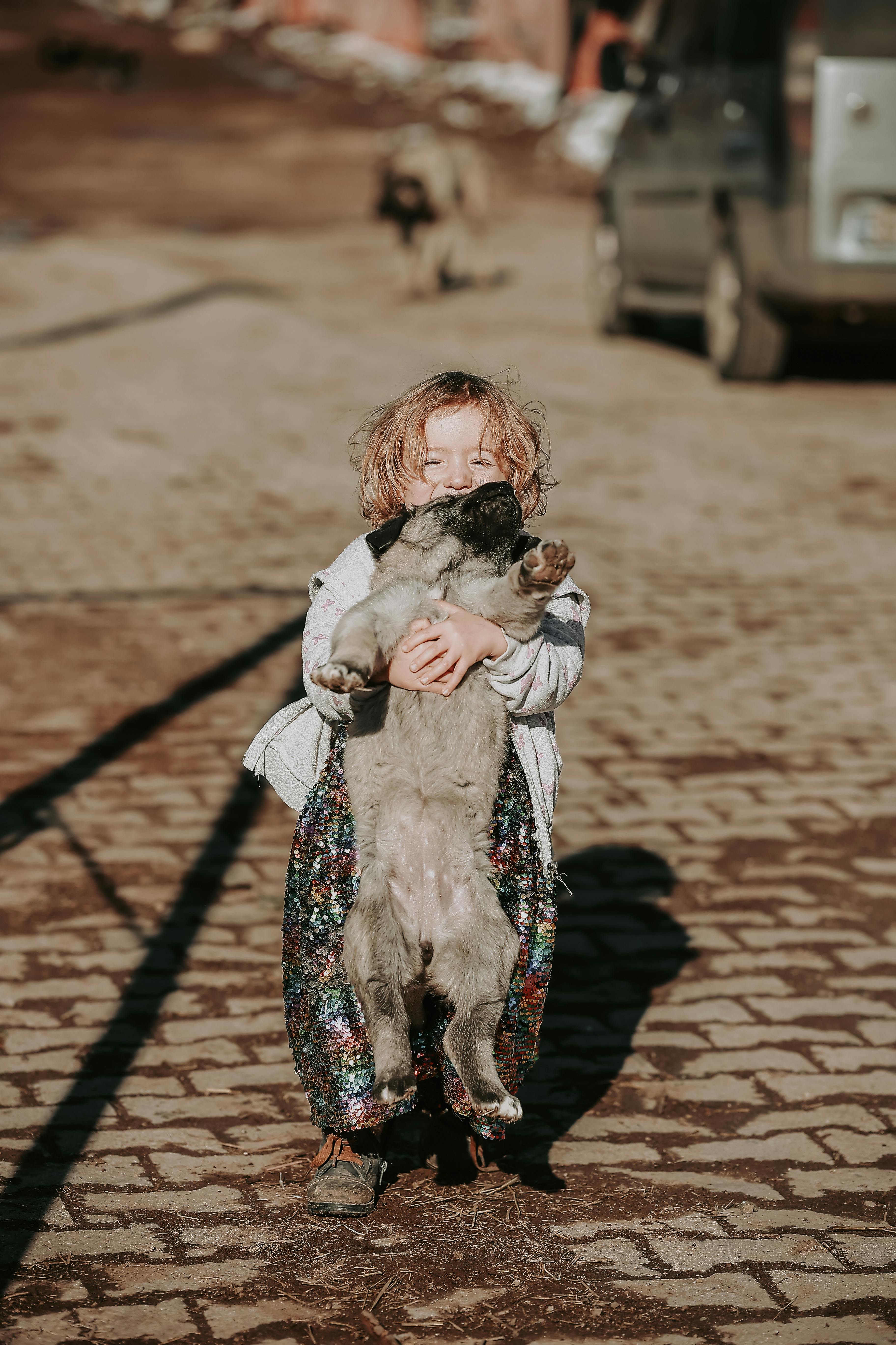 a little girl standing outside and holding a dog