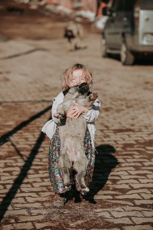A Little Girl Standing Outside and Holding a Dog 