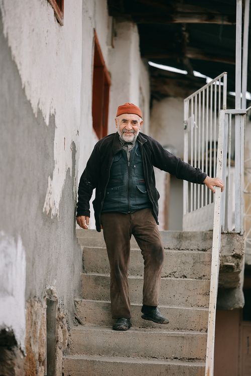 Free Happy elderly man with a beard standing on stairs outside a house in Sivas, Türkiye. Stock Photo