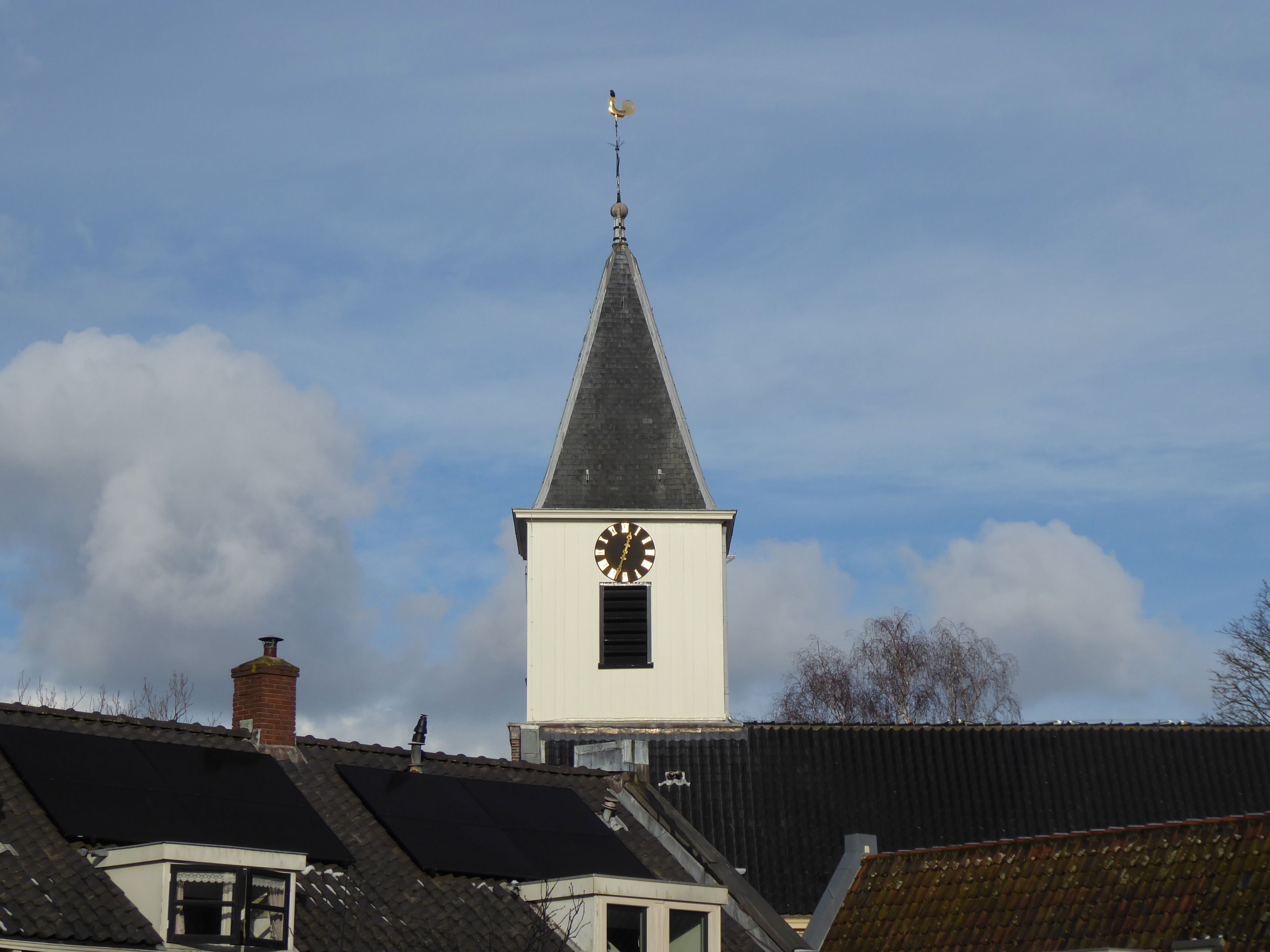 A picturesque church clock tower with a blue sky backdrop and scattered clouds.