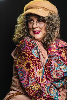 Portrait of a stylish senior woman wearing vibrant paisley-pattern clothing and eyeglasses.