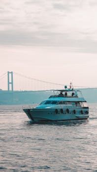 A luxury yacht cruising the Bosphorus with the iconic Istanbul bridge in the background.