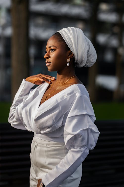 Elegant Woman in a White Dress and Turban Standing Outside 