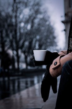 A person enjoys a warm coffee outdoors in rainy Bordeaux, France during winter.