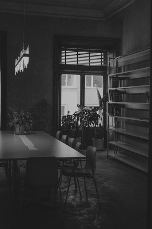 Black and White Photo of a Large Table with Chairs in the Middle of a Room 