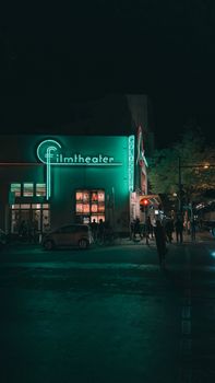 Dark and atmospheric photo capturing Berlin's film theater illuminated by neon lights at night.