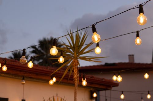 Free Outdoor string lights glow warmly in a Mediterranean setting, enhancing the evening atmosphere. Stock Photo