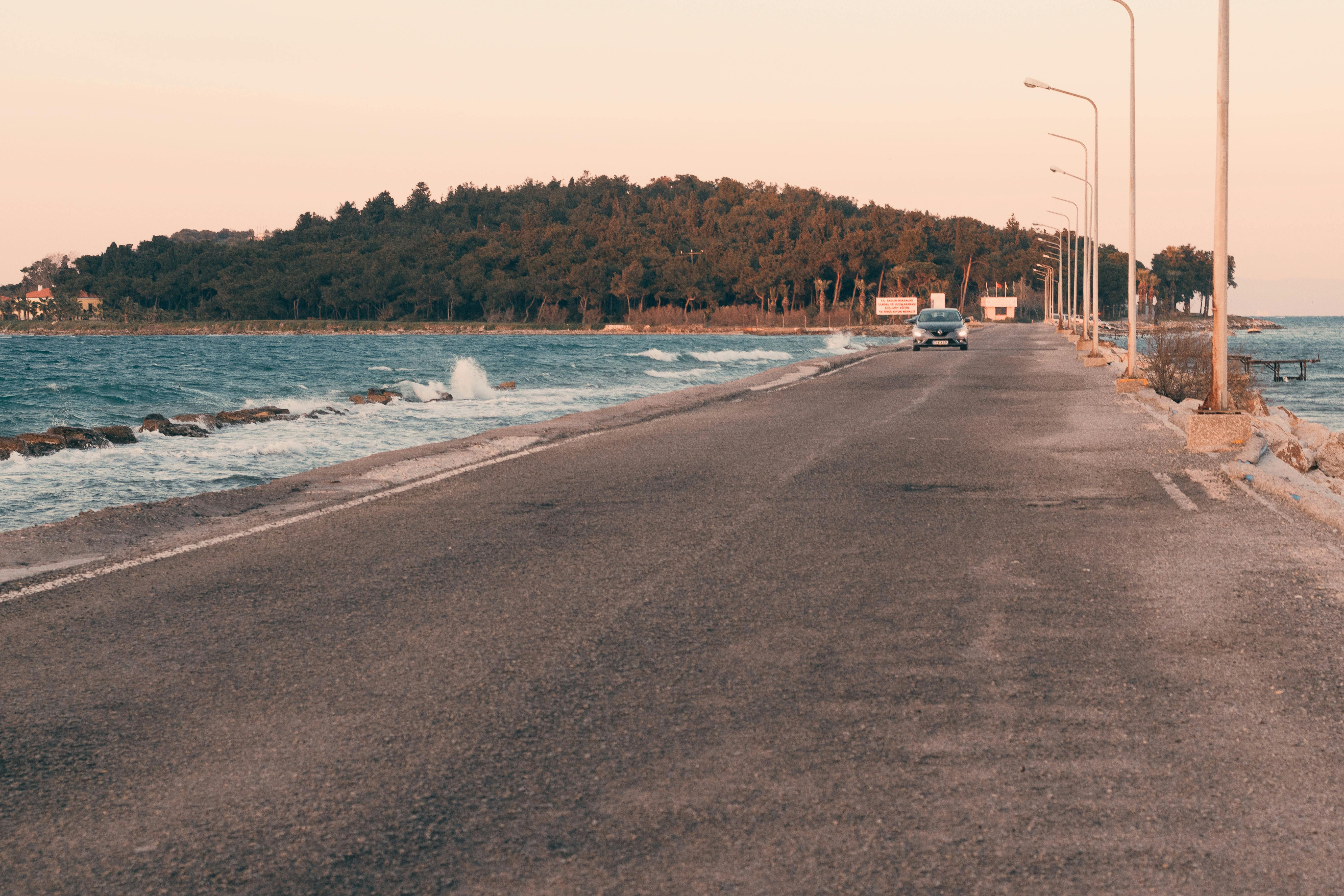 a long empty road with the ocean in the background