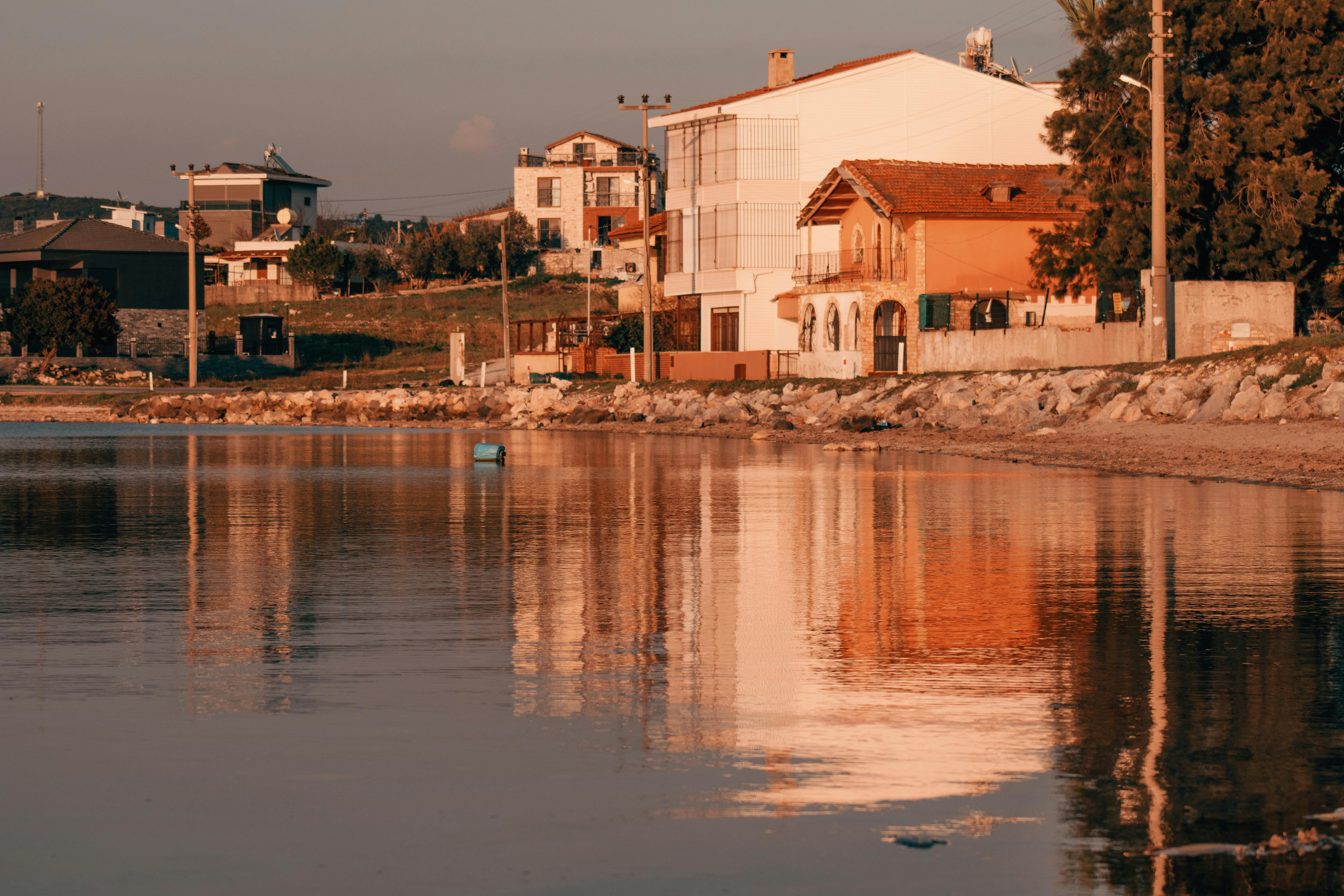 a house is reflected in the water near a beach