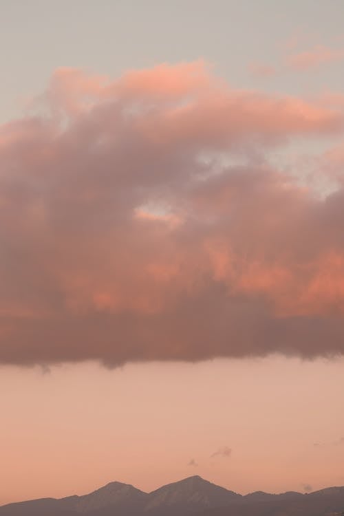 A pink cloud is seen over mountains