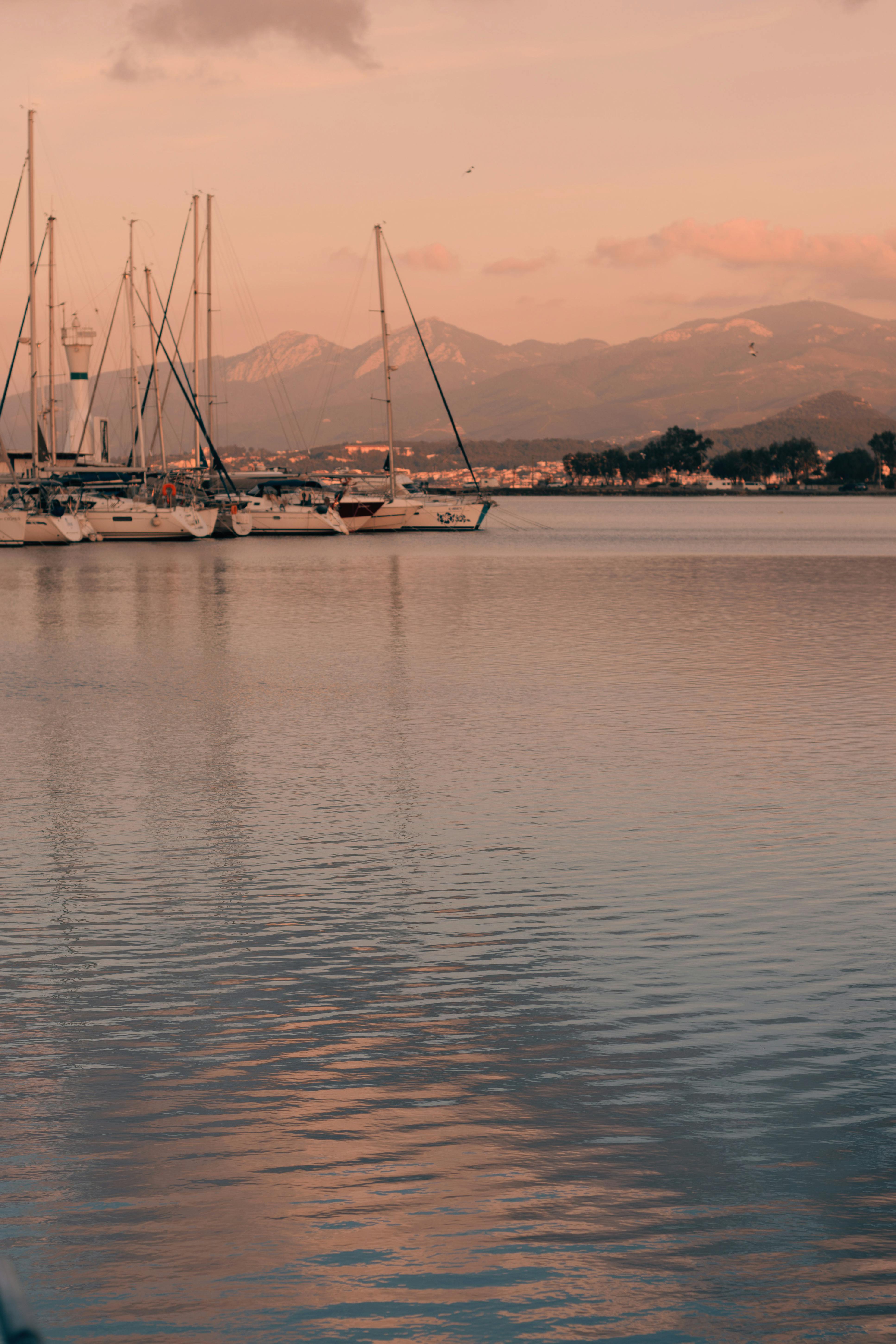 Peaceful evening view of sailing boats and mountains at Urla Marina in İzmir, Türkiye during sunset.