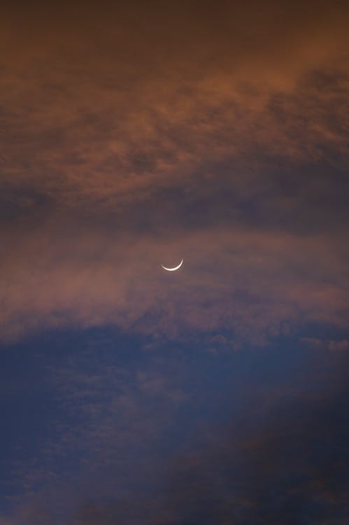 A crescent moon is seen in the sky with clouds · Free Stock Photo