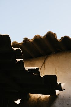 Close-up of an aged corrugated roof casting shadows on a sunny day.
