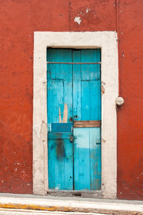 Free A rustic blue wooden door set in a vibrant red wall in Puebla, Mexico. Stock Photo