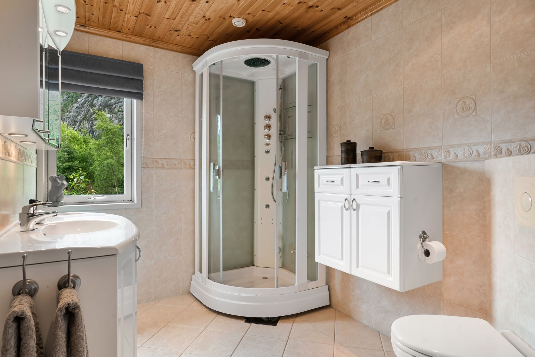 浴室窗戶太透明?無痕遮擋5招,隱私採光兩全 Bright and cozy bathroom featuring a glass shower, wooden ceiling, and a view of lush greenery through the window.