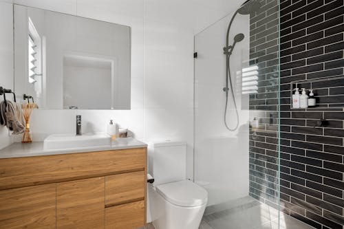 A bathroom with a white toilet and black tile