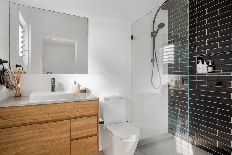 A contemporary bathroom featuring sleek black tiles, modern fixtures, and minimalist design.