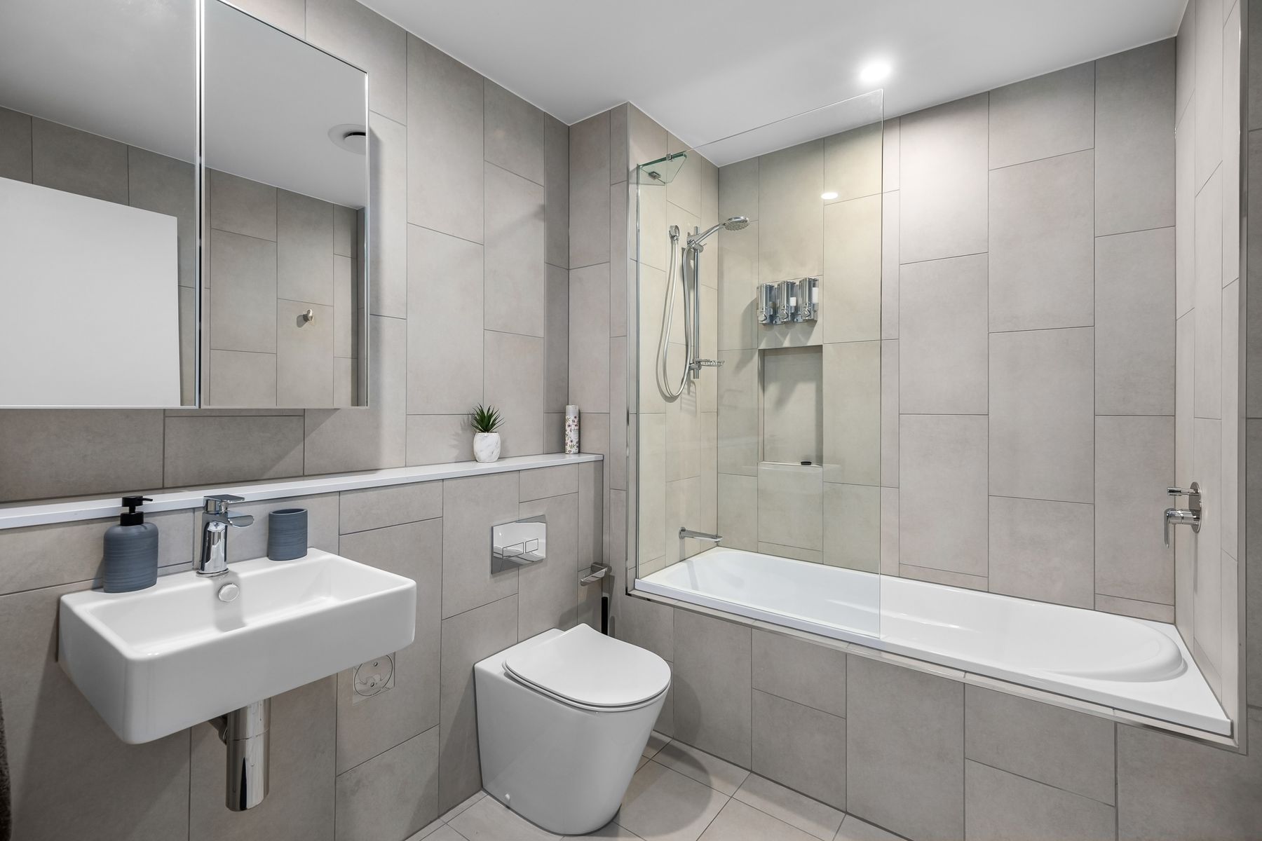 Modern minimalist bathroom with grey tiles and white bathtub