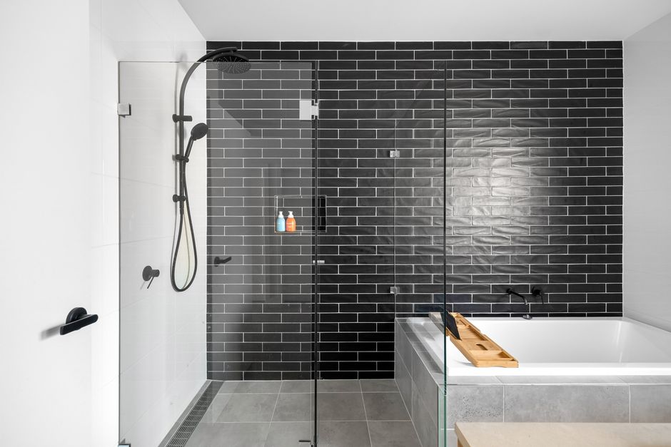 Photo by Lisa Anna on Pexels Sleek and modern bathroom featuring a black tiled wall and glass shower enclosure.