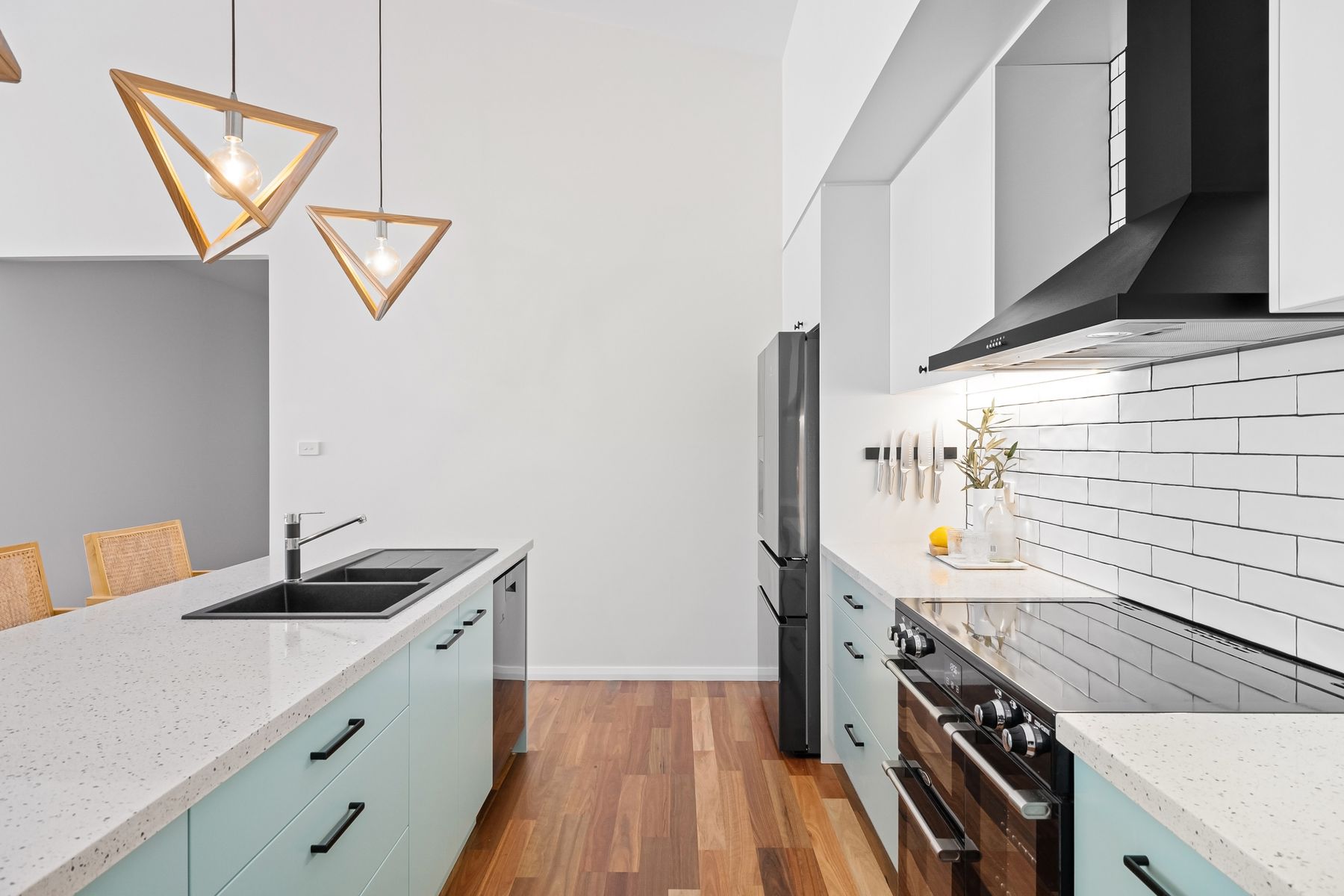 Quiet modern kitchen with central island and geometric pendant lighting