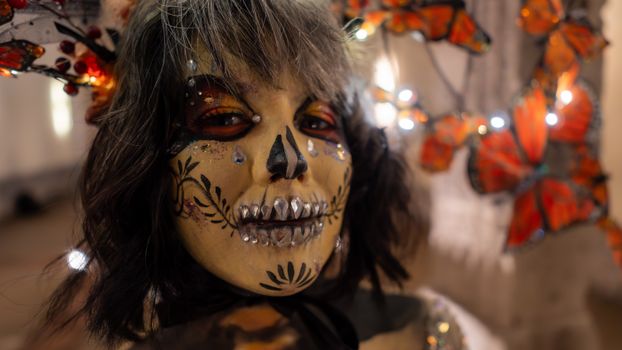 Close-up of a Catrina face painting for Day of the Dead, surrounded by butterfly decorations.