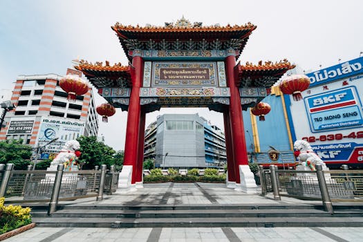 Vibrant Chinatown gate in Bangkok with surrounding urban cityscape.
